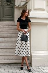 a lady in a black fitted top and a white skirt with printed black roses